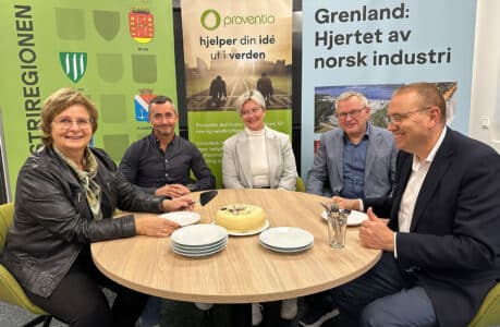 Fem personer rundt et bord med kake i midten