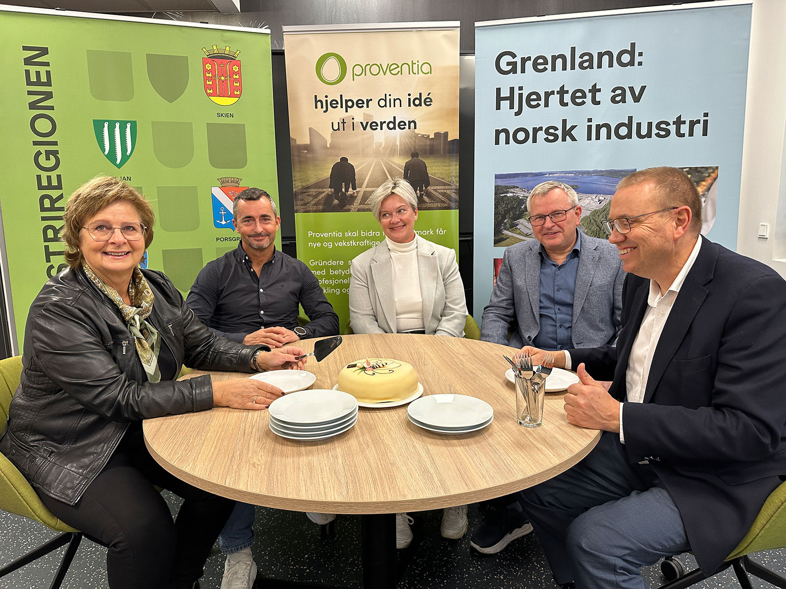 Fem personer rundt et bord med kake i midten